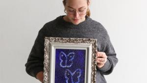 A woman holding a hunt slonem bunny painting with an antique frame.