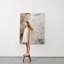 girl standing on a stool in front of painting 