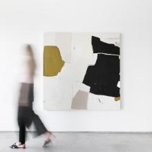 A person in motion walks past an abstract painting by Holly Addi mounted on a white wall. The piece, part of the Sunday Selects, features large, irregular shapes in black, olive green, beige, and white. The person is blurred due to the movement. 