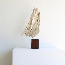 a teak erosion piece on a stand made a of wood sitting on a white pedestal against a white wall 