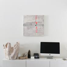 River Crossing Rivers by Patricia Larsen Minimalist workspace with a computer monitor, keyboard, and mouse set on a white desk. A beige bag, a small plant, and various stationery items are placed next to the monitor. An abstract painting with red and grey tones by Canadian artist Patricia Larsen is hung on the white wall above the desk.