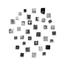 A photo showcasing a ceramic cube wall sculpture by Jodi Walsh, featuring various textured black and white blocks in a circular wall arrangement. 