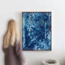 A vertical rectangular abstract painting by Kristen Abbott, featuring a predominantly blue color palette. White and lighter blue streaks and shapes create a dynamic, textured effect across the canvas, resembling leaves and organic patterns akin to cyanotype artwork. The painting is framed with a thin border.