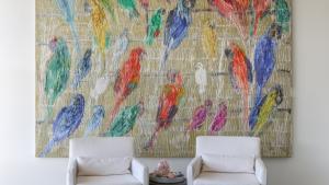 Hunt Slonem large Parrot painting with 2 chairs and an ottoman.