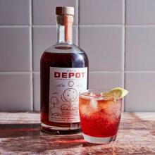 Picon punch drink in a glass with water and lemon sitting on a counter with Depot liquer.